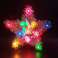 a multicolored star shaped ornament is lit up in the dark with colored lights