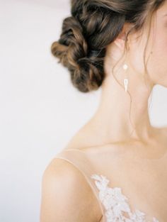 a woman in a wedding dress with her hair pulled back into a low bun and earrings