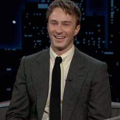 a smiling man in a suit and tie on the set of late show with jimmy stewart