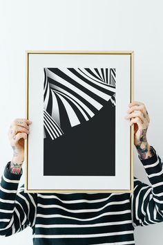 a woman holding up a black and white photo with an abstract design in it's frame