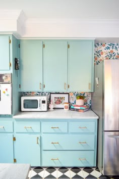 a kitchen with blue cabinets and floral wallpaper