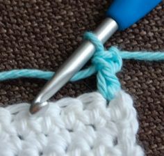 the crochet stitch is being worked on by a blue handled crochet hook