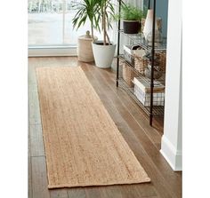 a rug on the floor in front of a window with potted plants next to it