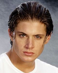 a close up of a person wearing a white t - shirt with water on his face