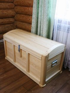 a large wooden trunk sitting on top of a hard wood floor next to a window