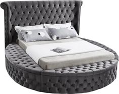 a round bed with white pillows and gray upholstered bedspread is shown