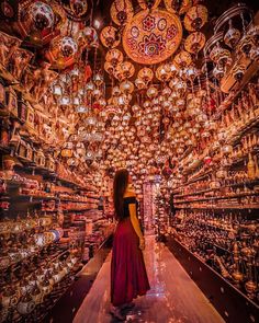 a woman in a red dress is looking at the ceiling full of glass globes