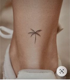 a small palm tree tattoo on the back of a woman's lower body,