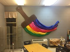 a room with a wall hanging made out of rainbow colored streamers on the wall