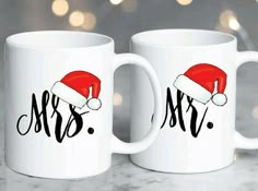 two white coffee mugs with santa hats on them, one has the word mr and mrs