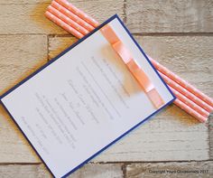 two orange and blue paper straws on top of a white envelope with an orange bow