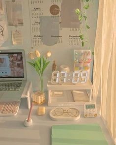 a desk with a laptop computer and various items on it, including flowers in vases