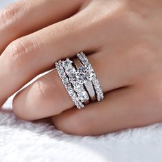 a woman's hand with an engagement ring and two wedding bands on her finger