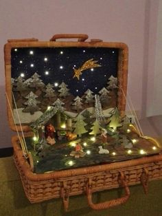 an open suitcase sitting on top of a floor covered in christmas lights and trees with a nativity scene inside