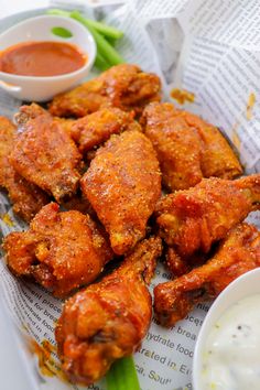 chicken wings with dipping sauce and celery sticks on a paper towel next to small bowls