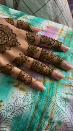 hendi tattoos on the hands of a woman with brown and green designs, sitting on top of a bed