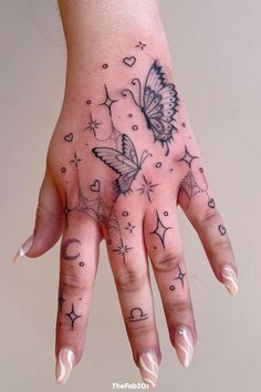 a woman's hand with tattoos on it and two butterflies flying above the fingers