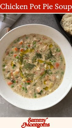 a white bowl filled with chicken pot pie soup on top of a table next to bread