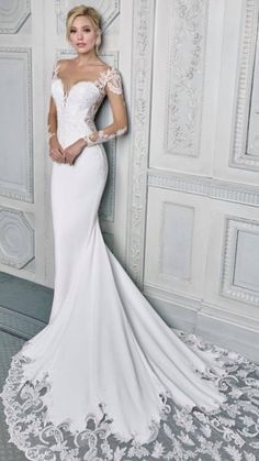 a woman in a white wedding dress leaning against a wall with her hands on her hips