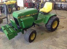 a green tractor parked inside of a garage