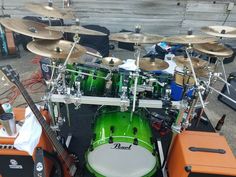 a green drum set sitting on top of an orange case next to other musical equipment