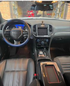 the interior of a car with black leather seats and blue dash board, steering wheel and center console