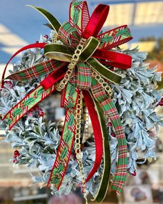 a christmas wreath with red, green and gold ribbon hanging from it's center