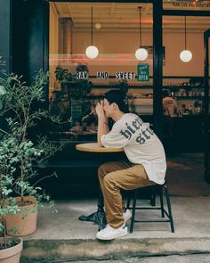 a man sitting at a table in front of a store