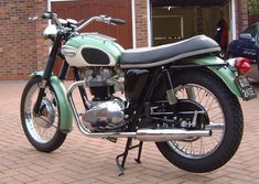 a green motorcycle parked in front of a brick building