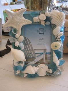 a blue frame with shells and seashells on the bottom is sitting on a table