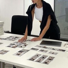 a woman standing over a table with pictures on it