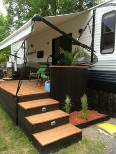 a camper with stairs leading up to the front door and back porch area next to it