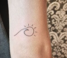 a small sun and wave tattoo on the left inner arm, which is black and white