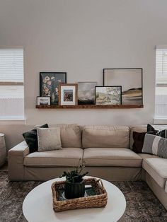 a living room filled with furniture and framed pictures on the wall over a coffee table