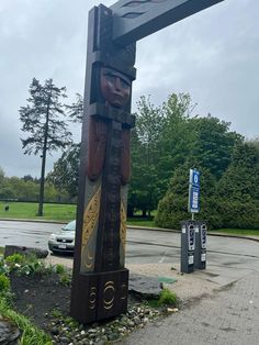 a large wooden cross sitting on the side of a road next to a parking lot