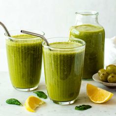 two glasses filled with green smoothie on top of a table