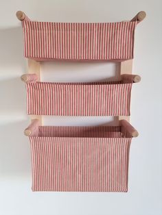 three red and white striped storage baskets hanging from the side of a wall in a room