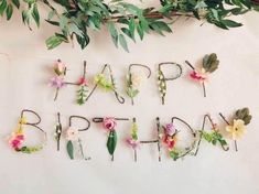 the word happy birthday spelled with flowers and greenery on a white surface surrounded by branches