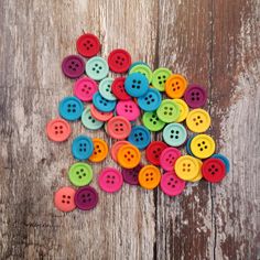 many different colored buttons on a wooden surface