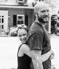 a man and woman standing in front of a house covered in soapy water on a sunny day