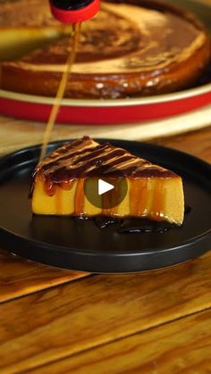 a piece of cheesecake on a black plate with caramel sauce drizzled over it