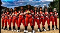 a group of women in red uniforms standing on a baseball field with their hands together