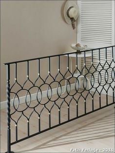 a black iron railing with white lights on it in front of a beige wall and floor