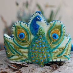 a blue and green peacock headband sitting on top of a piece of wood