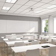 an empty classroom with white desks and chairs