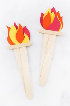 two popsicle sticks with flames on them sitting next to each other in front of a white background