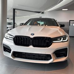 the front end of a white bmw car in a showroom