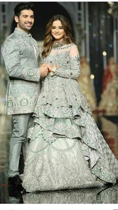 two people standing next to each other on a runway wearing wedding gowns and tuxedos