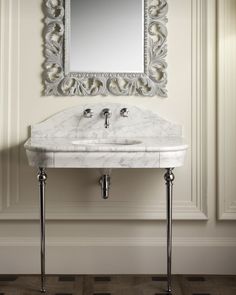 a white sink sitting under a mirror next to a wall mounted faucet in a bathroom