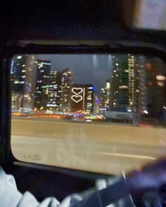 a view of the city from inside a car window at night with buildings in the background